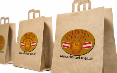 Bedruckte Papiertragetaschen von Goldenes Schnitzel mit Logo und Webadresse